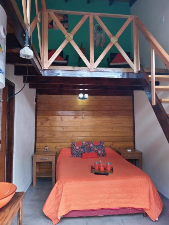 1 dormitorio con cama roja y paredes de madera en El Paraiso en San Clemente del Tuyú