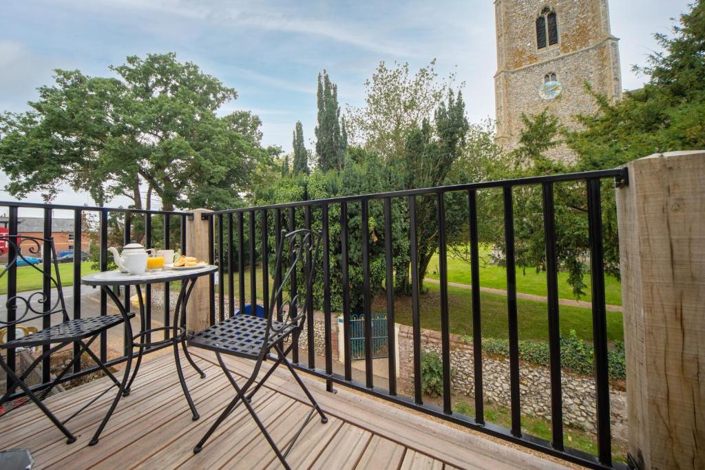a balcony with a table and chairs and a church at The Hideaway in Great Massingham