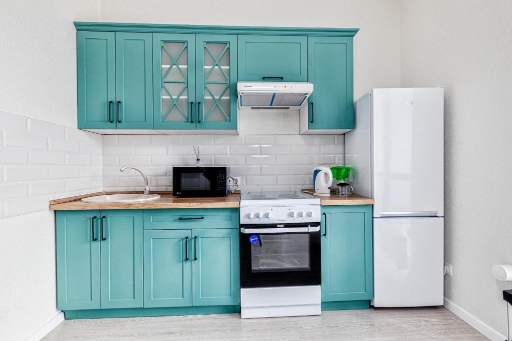 a kitchen with blue cabinets and a white refrigerator at Raisson Ahotel H252 in Taldykolʼ