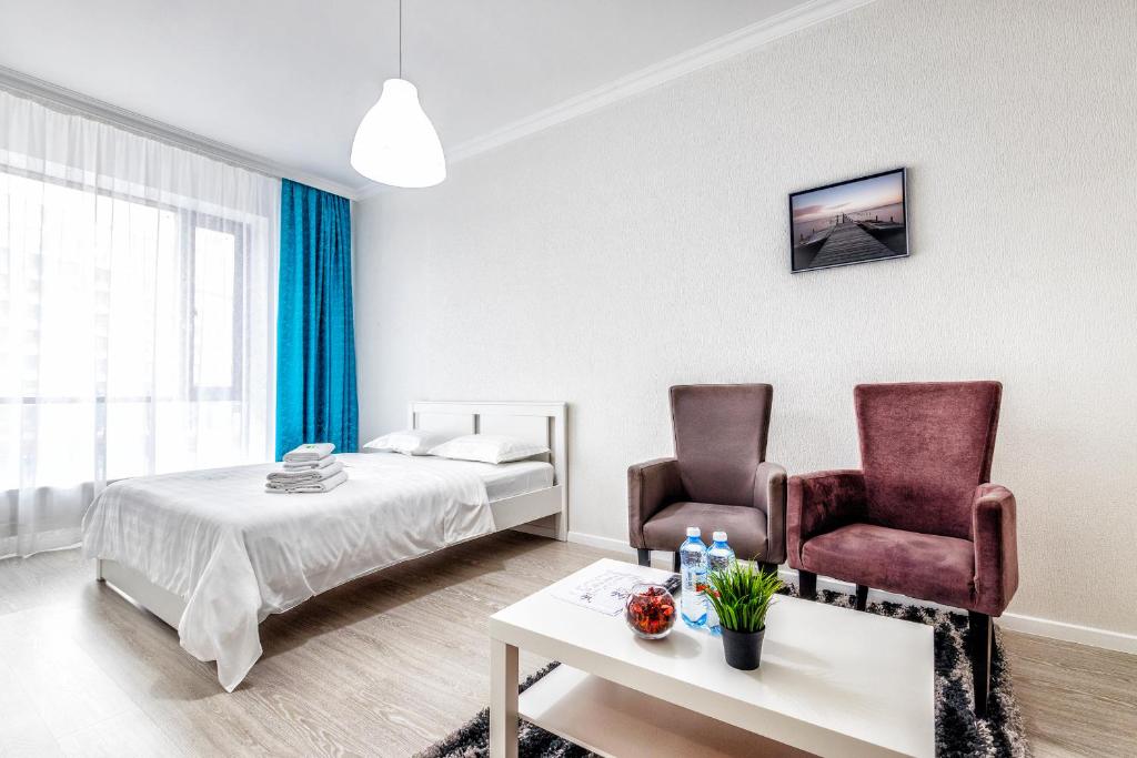 a bedroom with two chairs and a bed and a table at RAISSON APARTHOTEL H252 Хан Шатыр in Taldykolʼ