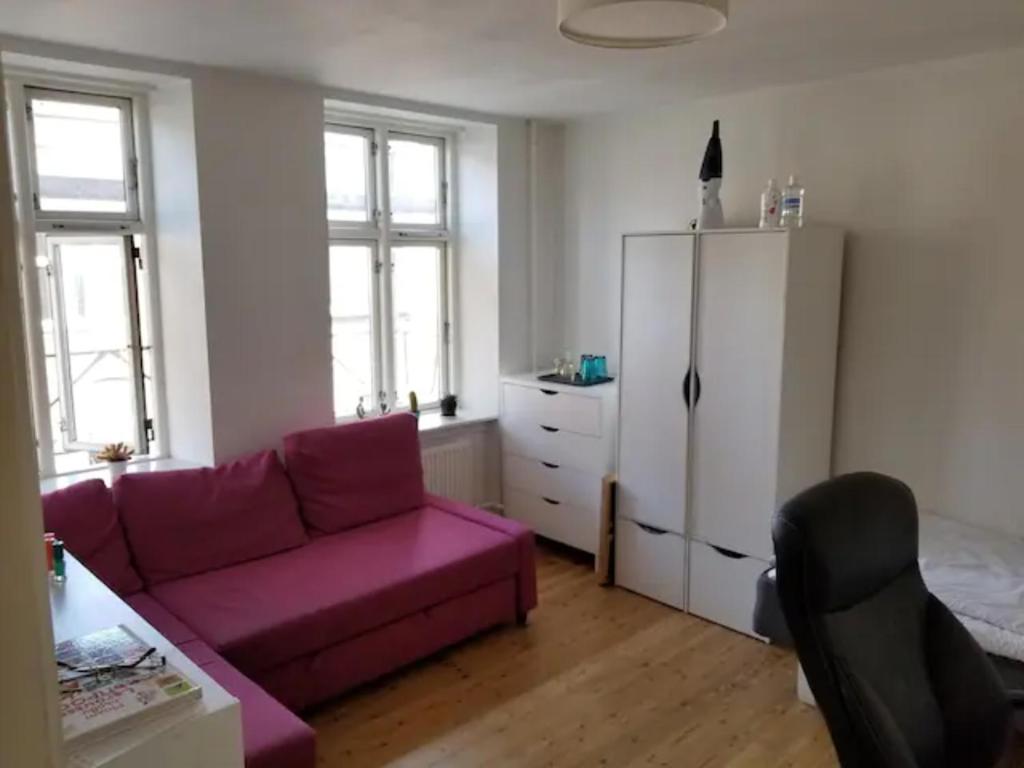 a living room with a purple couch and a refrigerator at Bright & Cozy Room in Zone 1 in Copenhagen