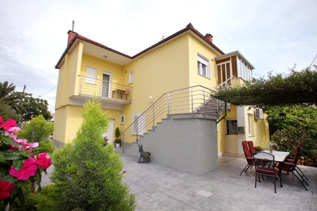 Casa amarilla con escalera y patio en Apartment Tinel, en Trogir