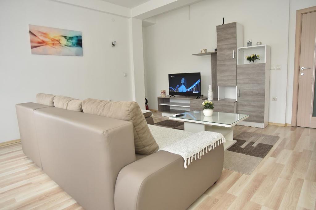 sala de estar con sofá blanco y TV en SOKOLANA Apartments, en Kumanovo