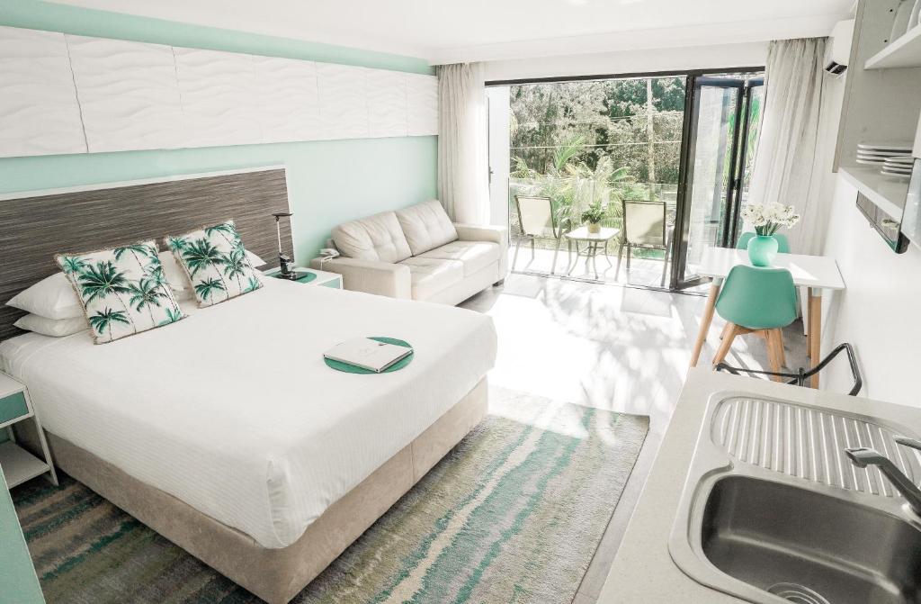 a bedroom with a bed and a sink and a couch at Terrigal Pacific Coastal Retreat in Terrigal