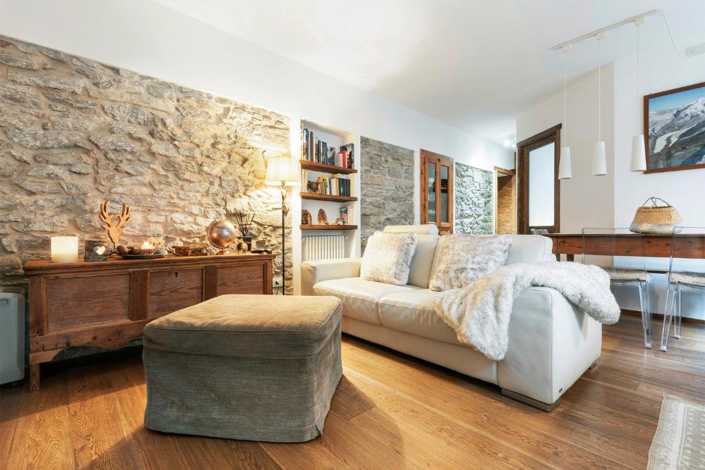 un soggiorno con divano bianco e parete in pietra di Appartamento Casa Weisstor con patio, giardino e orti vista Monte Rosa a Macugnaga