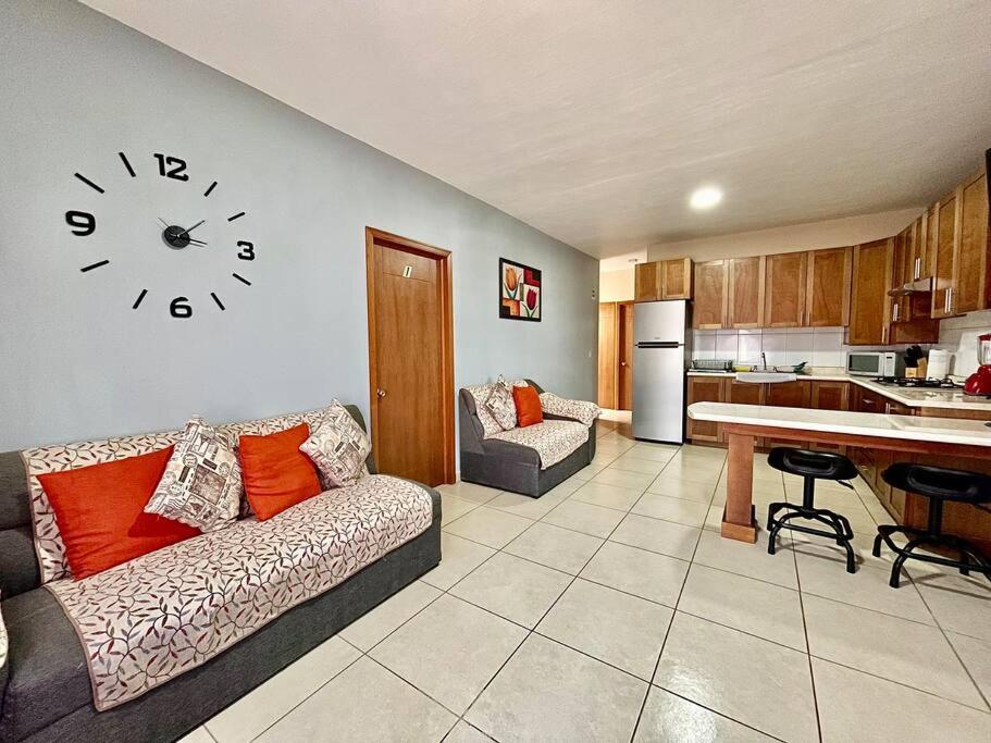 Ocotlán的住宿－Gallery Home，客厅配有沙发和墙上的时钟
