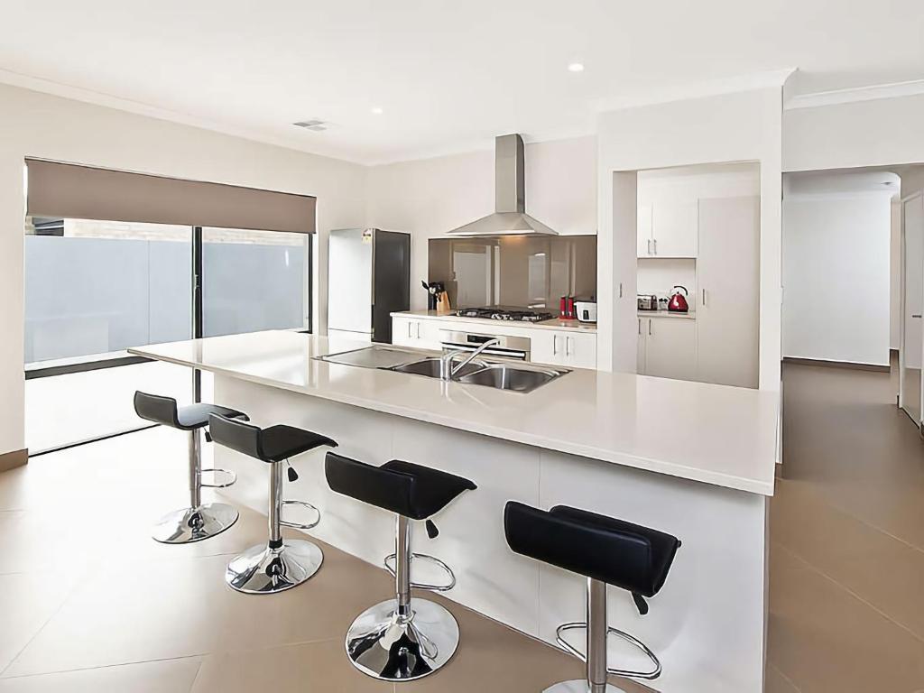 a kitchen with a white counter and bar stools at Ocean Walk Abbey in Vasse