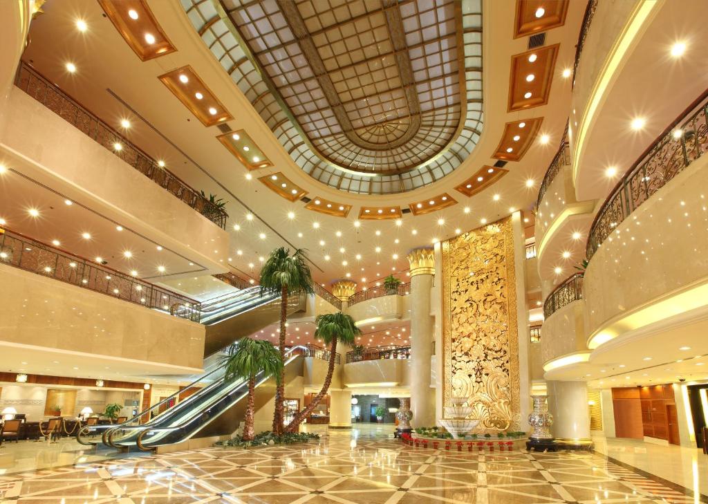 a lobby with escalators and palm trees in a building at Beijing New Century Hotel in Beijing
