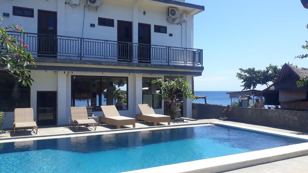 una piscina frente a un edificio con sillas en Pakel's Bali Villas, en Amed