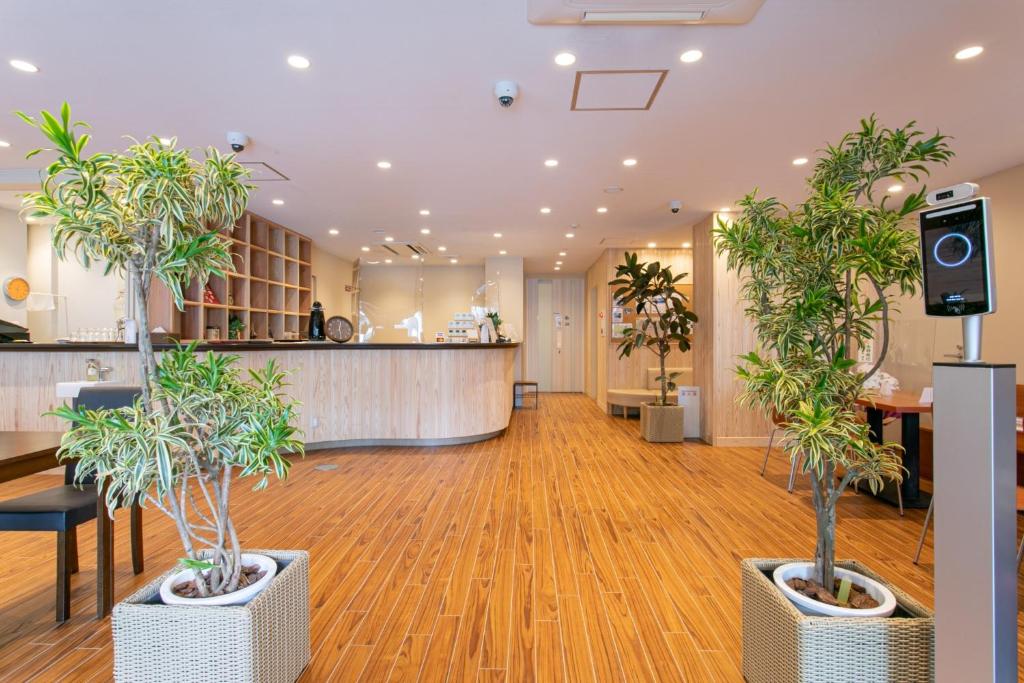 a lobby with two potted trees and a counter at Bakery Hotel Chateau D'or in Nara