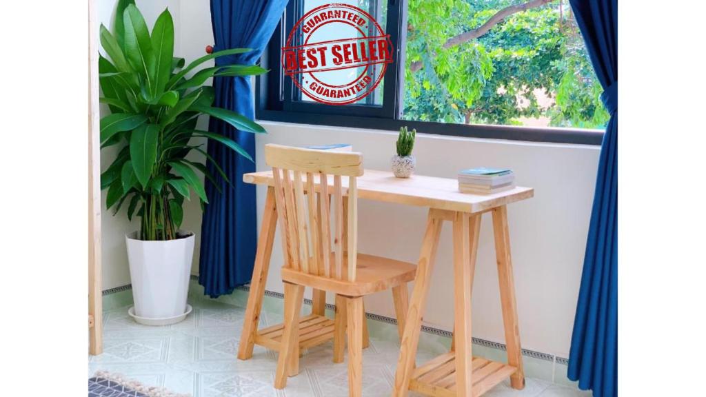 een houten tafel en stoel naast een raam bij Xoài Xanh Hostel & Villa in Vung Tau