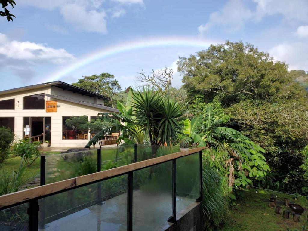 a rainbow in the sky above a house with a pond at OutBox Inn in Monteverde Costa Rica