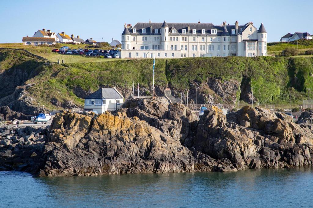 波特帕特里克的住宿－The Portpatrick Hotel by Compass Hospitality，悬崖顶部的城堡,靠近水面