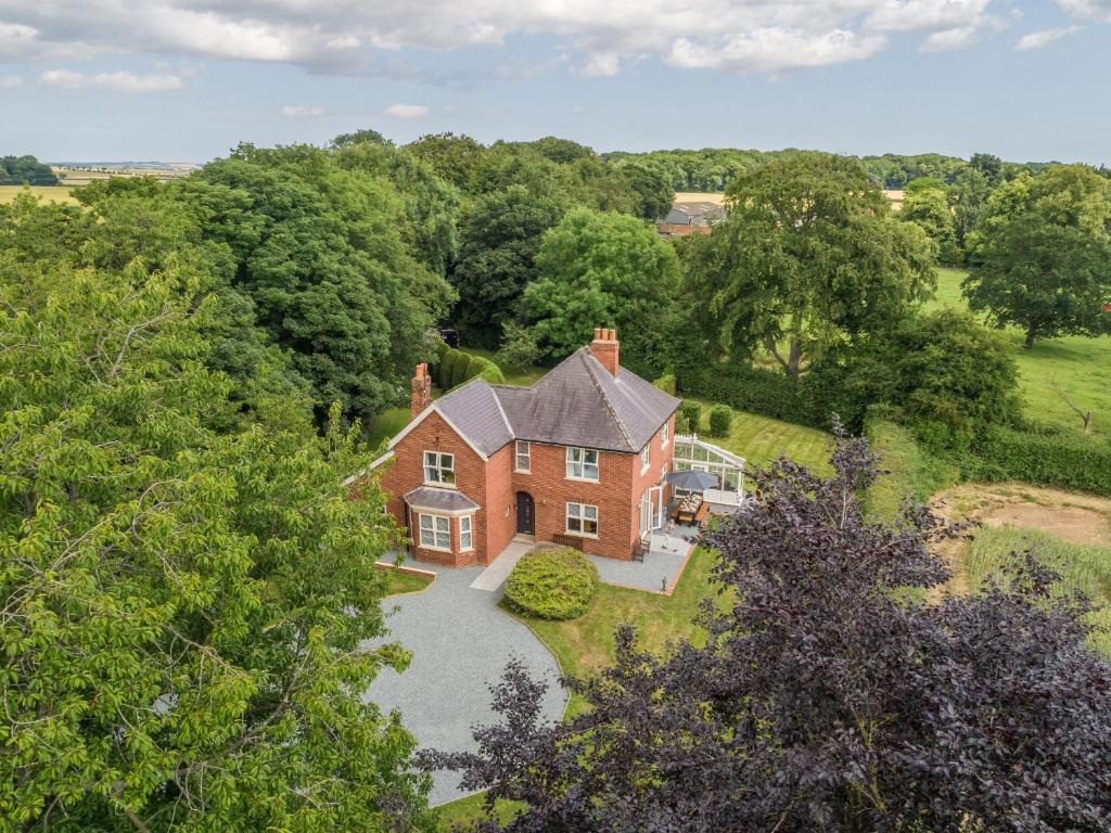 una vista aérea de una gran casa de ladrillo con entrada en Routhorpe House en Bainton