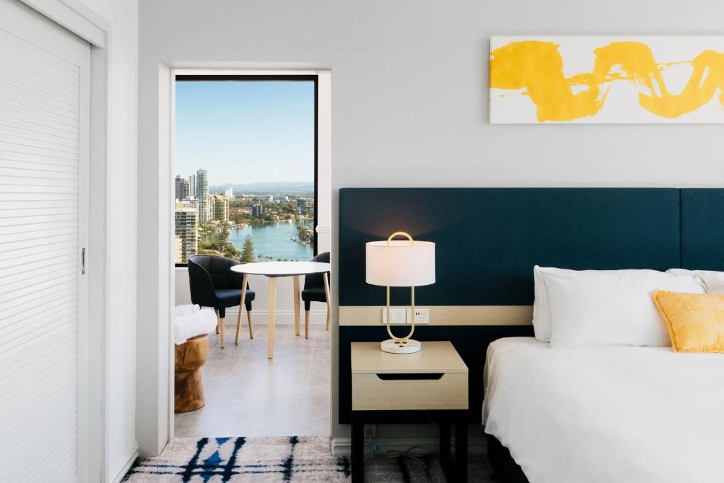 voco Gold Coast, an IHG Hotel في غولد كوست: غرفة نوم بسرير وطاولة مع مصباح