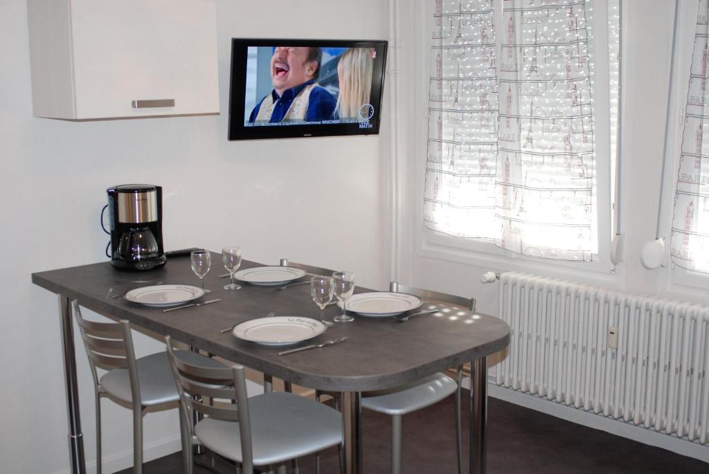 a dining room table with chairs and a tv on the wall at myappartepinalF1 in Épinal