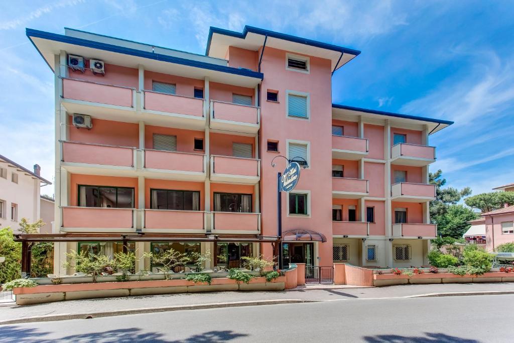 un bâtiment rose avec un toit bleu dans l'établissement Hotel Valentino, à Pinarella