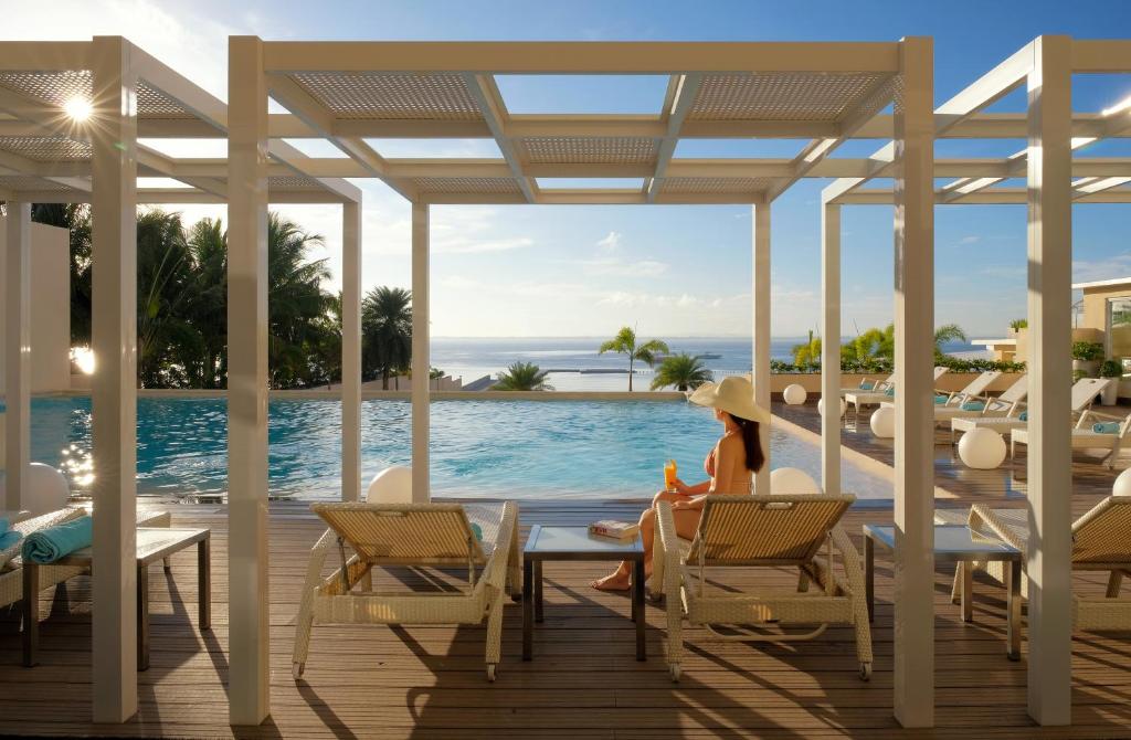 a woman sitting on a deck looking out at the ocean at BE Resort Mactan in Mactan