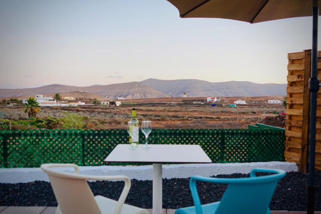 a table with a glass of wine and two chairs at Siempre Feliz La Casita Los Molinos in Villaverde