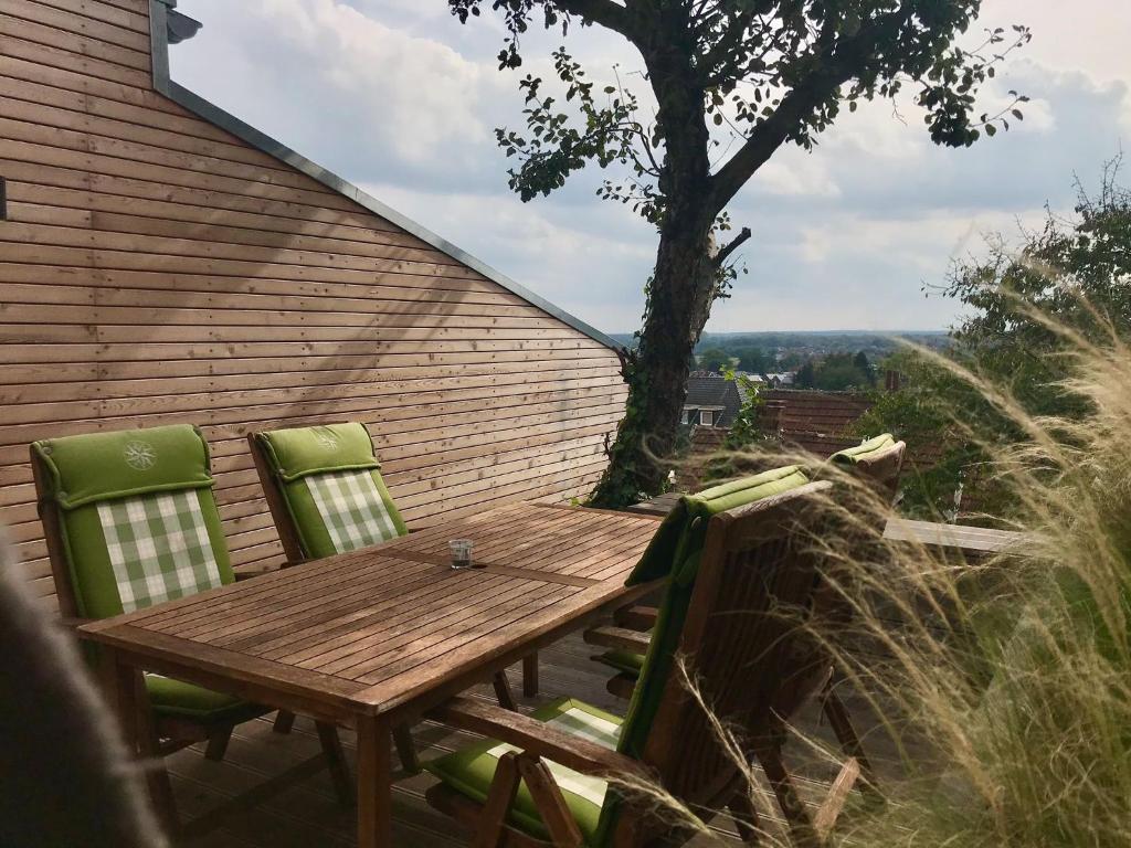 - une table en bois et 2 chaises vertes sur la terrasse dans l'établissement Gemütliches Bergappartement mit Weitblick, à Bad Bentheim
