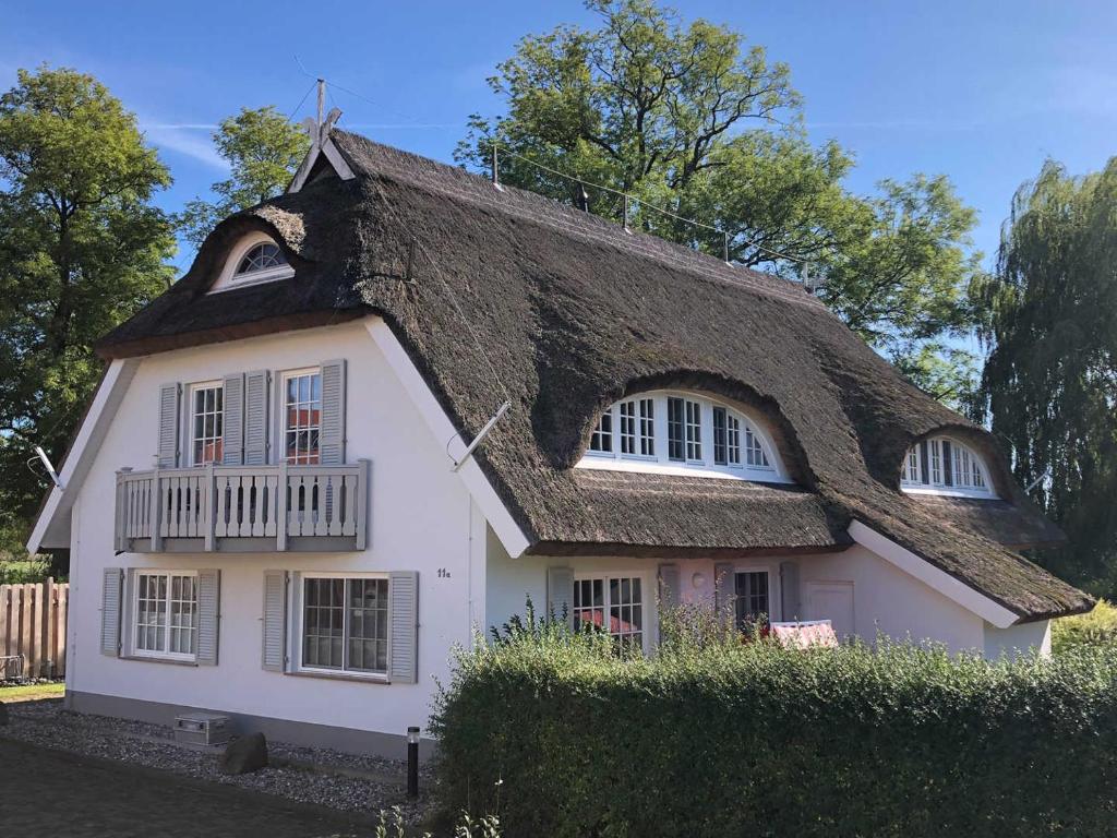 ein Cottage mit einem Strohdach darüber in der Unterkunft Landhaus am Teich in Middelhagen