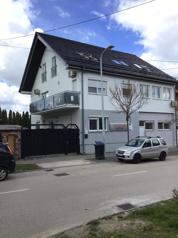 a white house with a car parked in front of it at Dózsaház in Zalaegerszeg