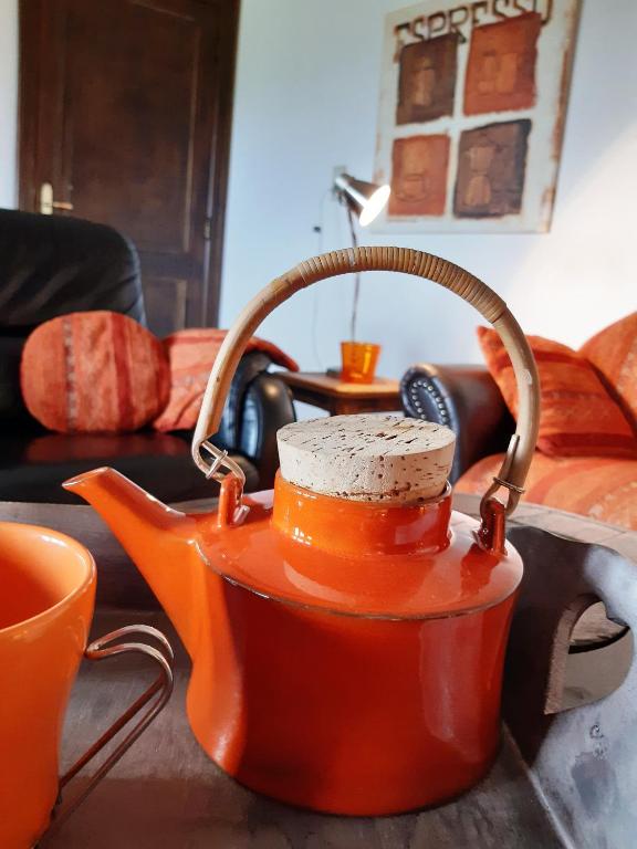 an orange tea kettle sitting on top of a table at La Pause in Plombières