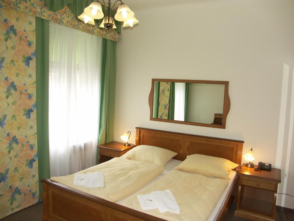 Schlafzimmer mit einem Bett und einem Spiegel an der Wand in der Unterkunft Brezina Pension in Prag