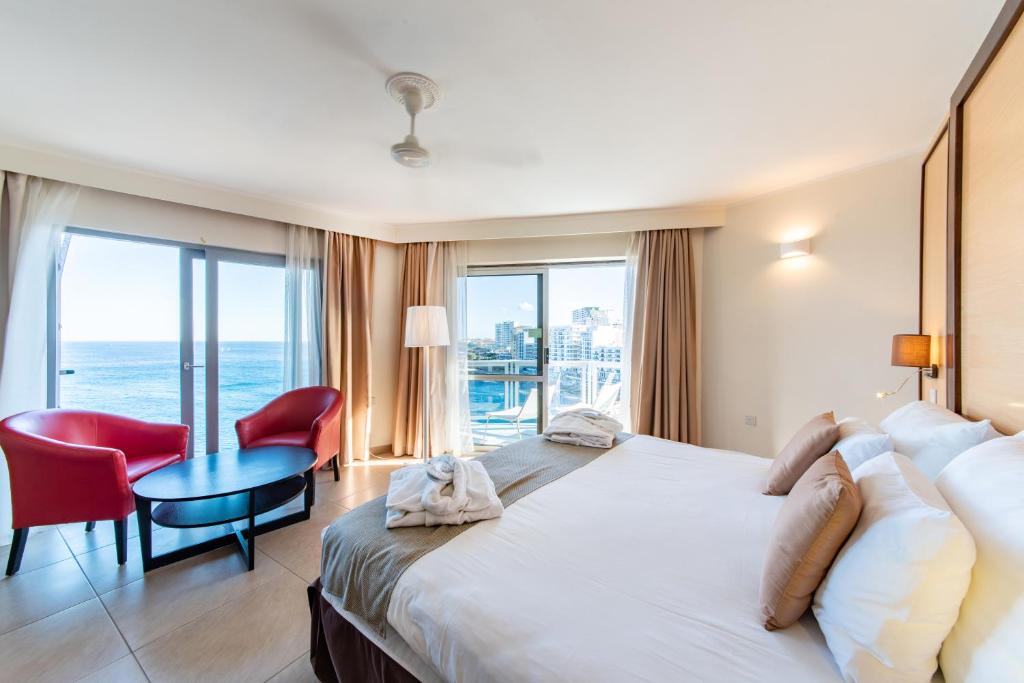 a hotel room with a large bed and a table and chairs at The Preluna Hotel in Sliema