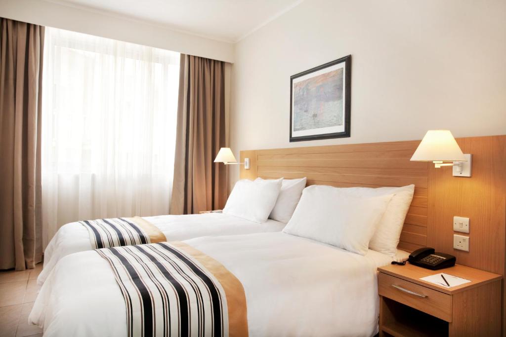 a hotel room with two beds and a phone on a table at The Preluna Hotel in Sliema