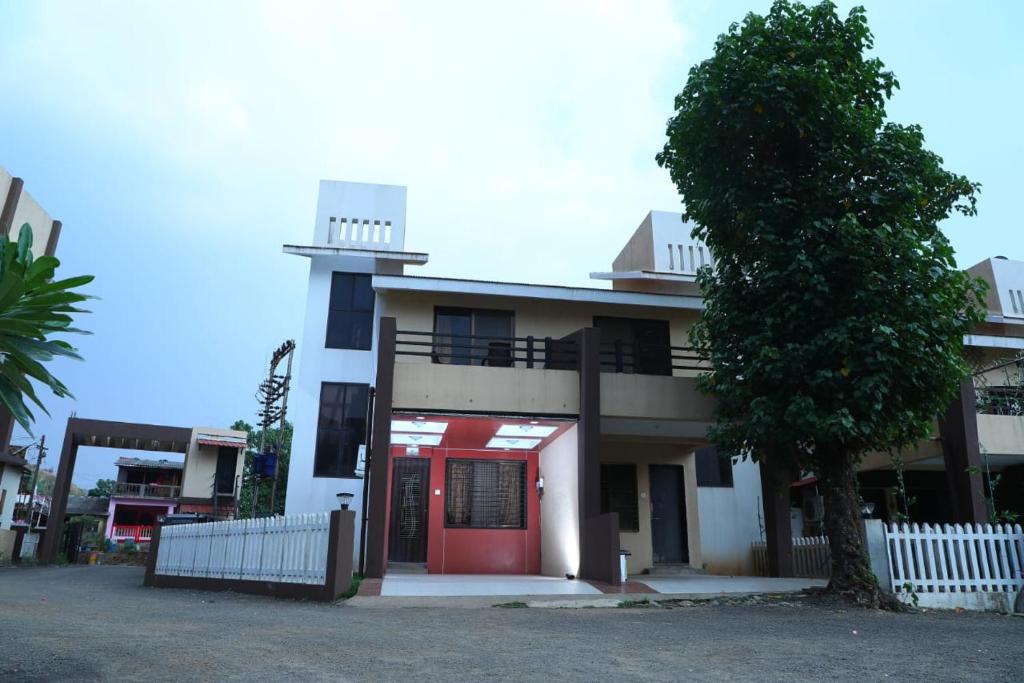 a building with a red door and a tree at Akshaya Villa in Lonavala