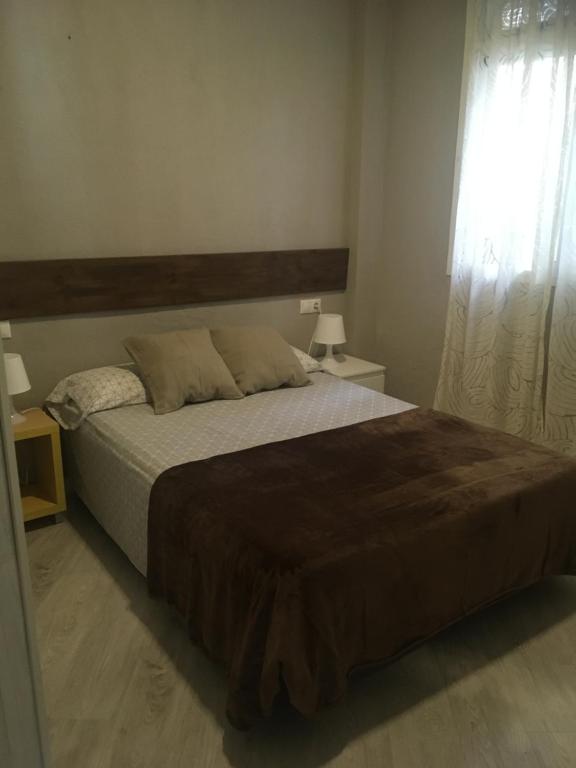 a bedroom with a large bed and a window at Apto con patio y barbacoa BBQ H de la Reina in Córdoba