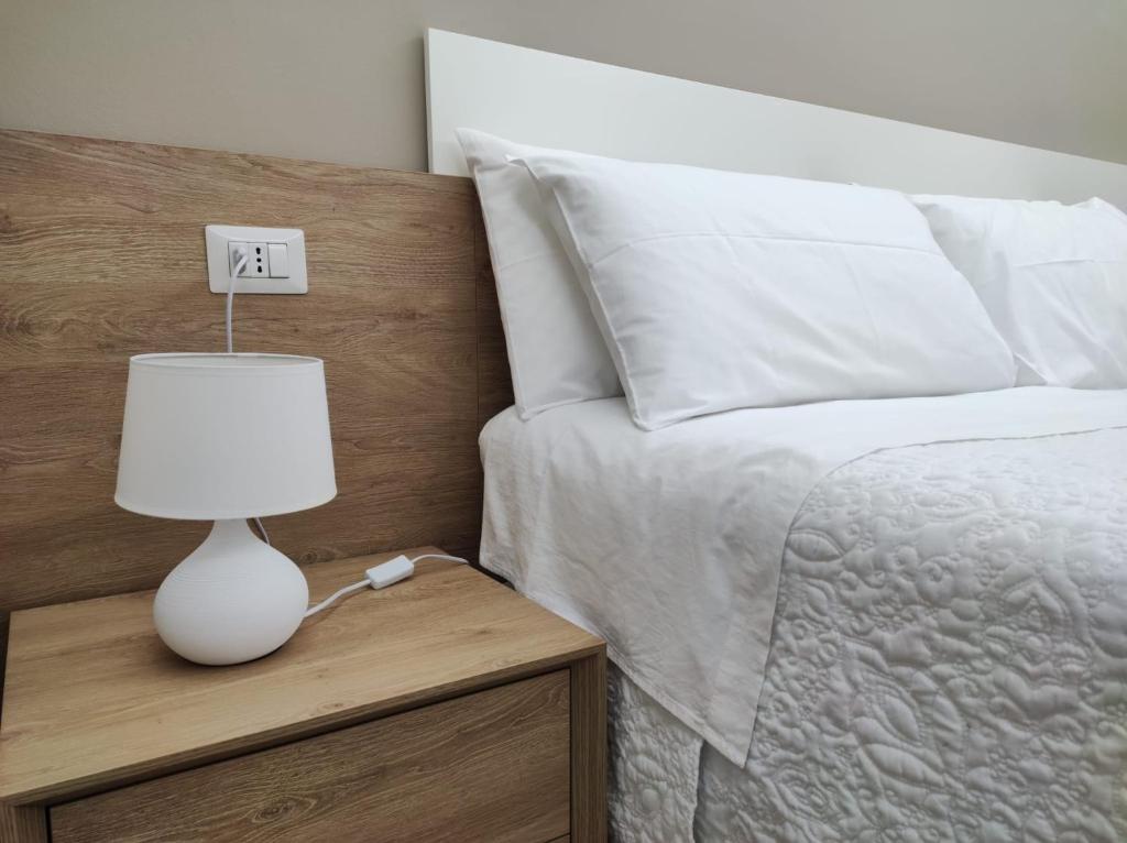 uma lâmpada branca numa mesa de cabeceira ao lado de uma cama em Porta d'Alpi em Latronico