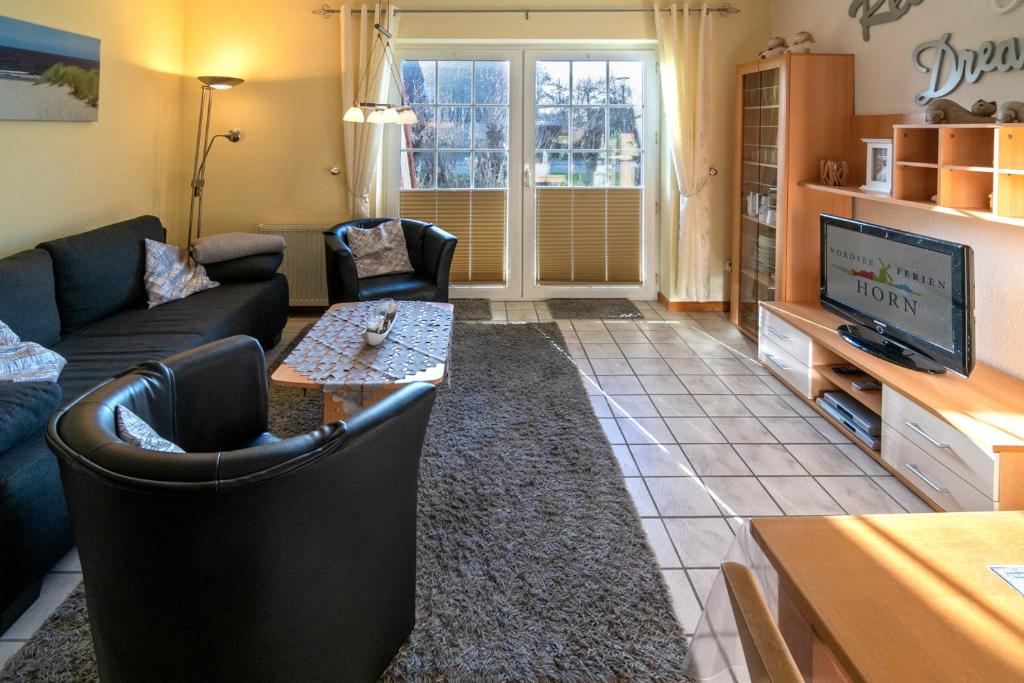 ein Wohnzimmer mit einem Sofa und einem TV in der Unterkunft Herta in Neßmersiel