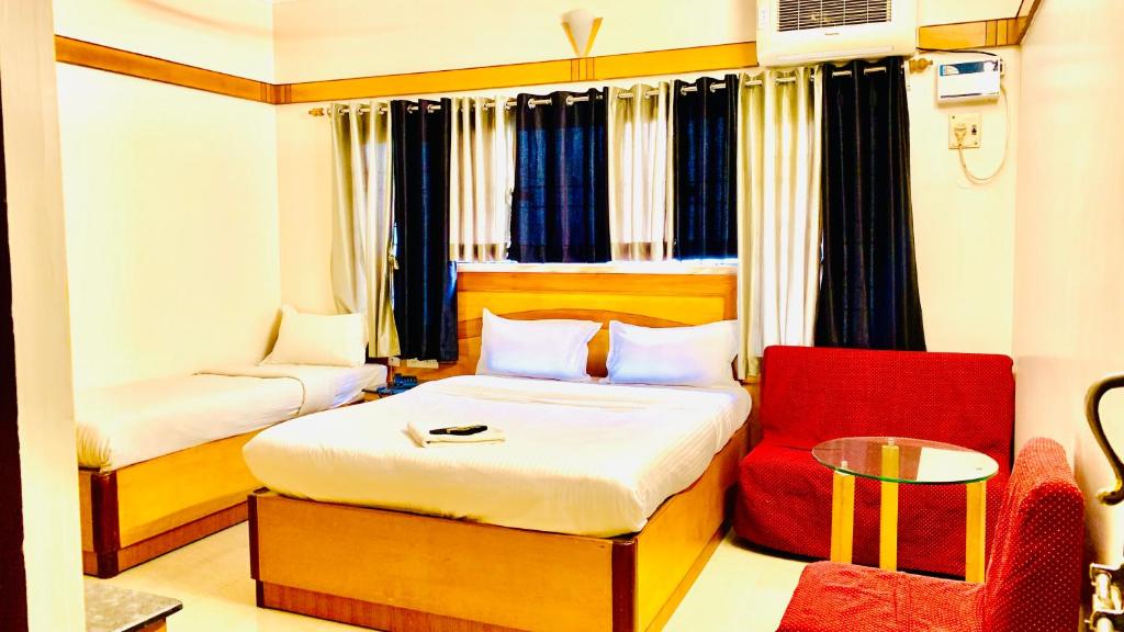 a bedroom with a bed and a red chair at Half Moon Palace Chennai in Chennai