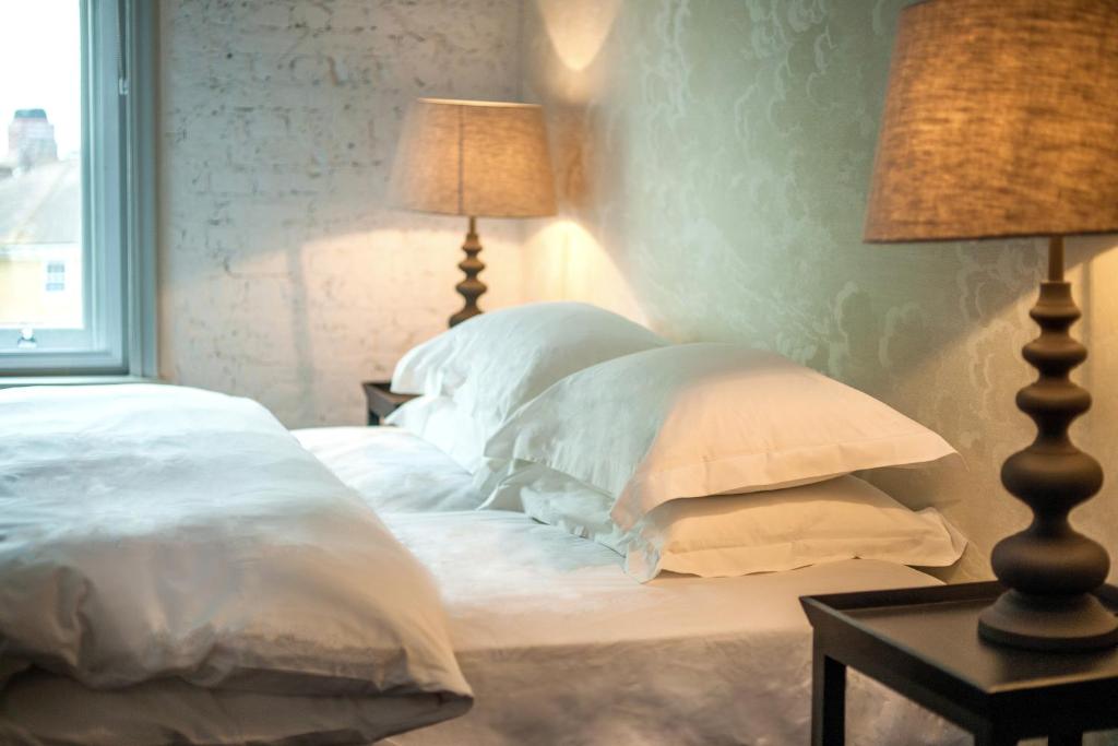 a bed with white sheets and pillows next to a window at The Tommyfield Hotel in London