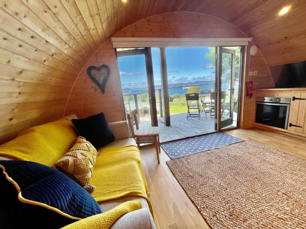 uma sala de estar com um sofá e vista para o oceano em Sutor Coops The Den with Hot Tub em Cromarty