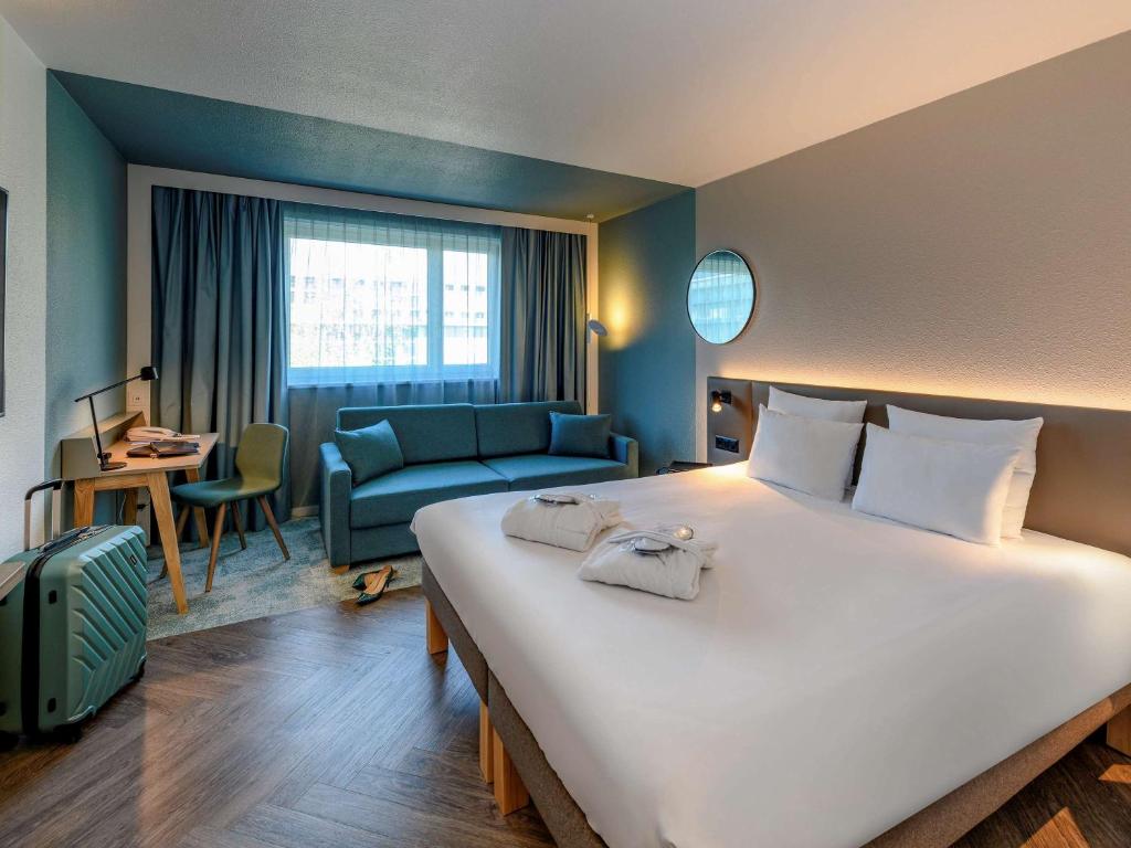 um quarto de hotel com uma cama grande e um sofá em Novotel Zurich City West em Zurique