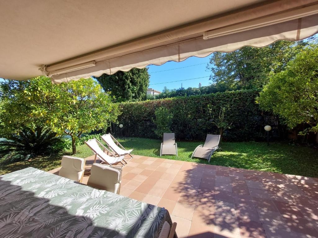 a patio with chairs and a bed and an umbrella at Plage la Salis 3 chambres, Jardin - 3 bedrooms in Antibes