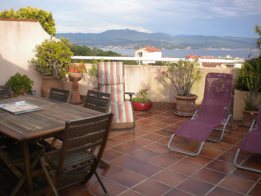 een patio met een houten tafel en stoelen bij Chambre hôtes Wagram in Ajaccio