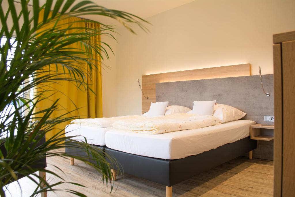 a bedroom with a bed with white sheets and pillows at Motel Lohwasser in Lichtenau