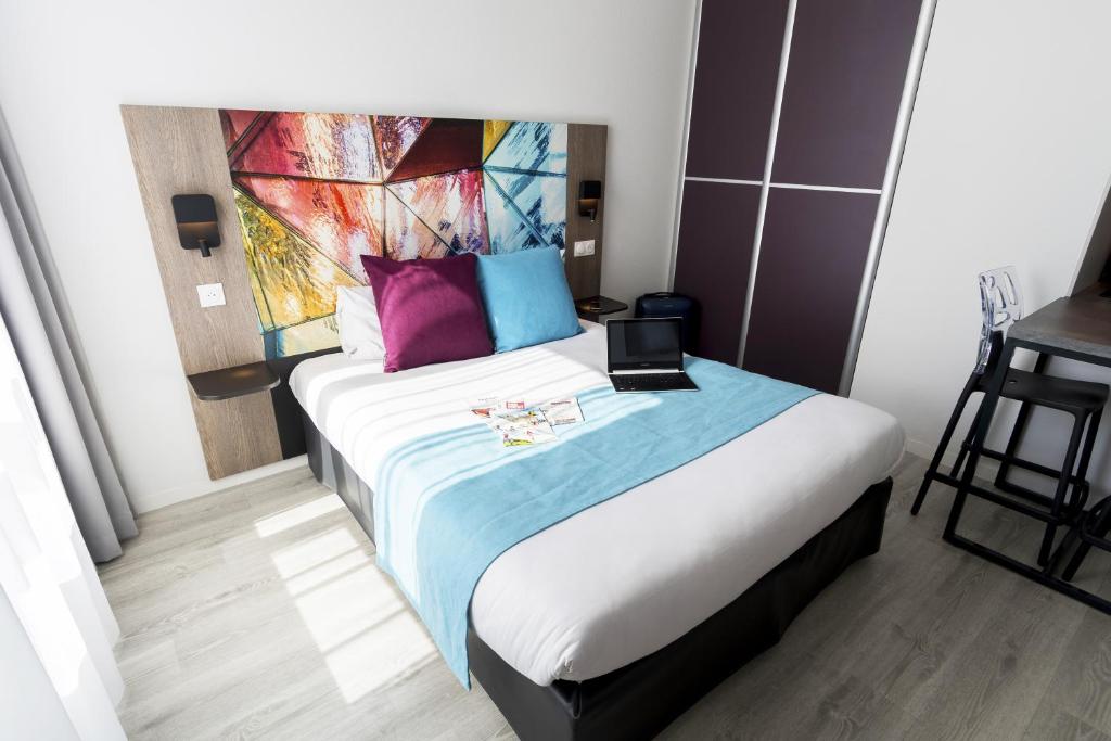 a hotel room with a bed with a laptop on it at Appart-Hôtel Mer & Golf City Bordeaux Lac in Bordeaux