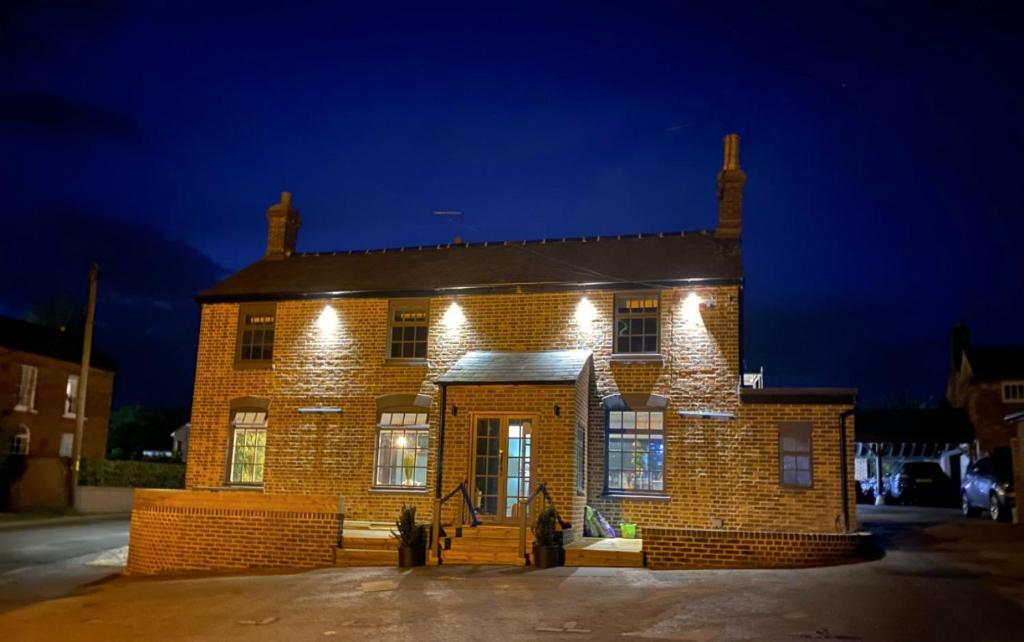 um edifício de tijolos com luzes acesas à noite em The Cherry Tree em Kingston Blount