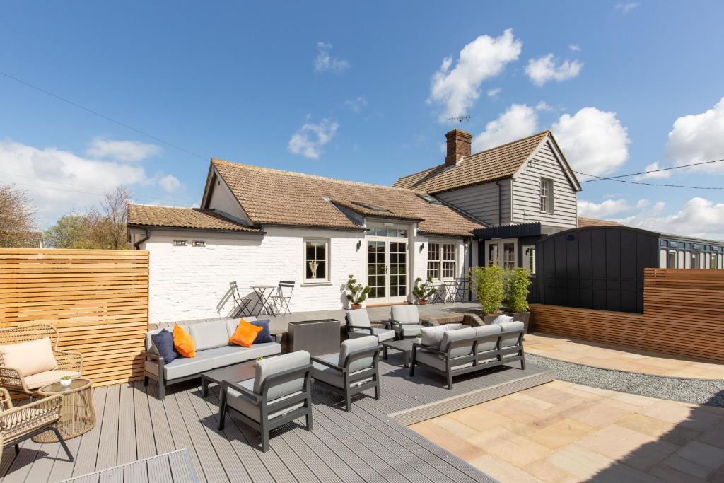 a patio with couches and chairs on a wooden deck at The Railway Hotel by Barefoot Retreats in Burnham Market