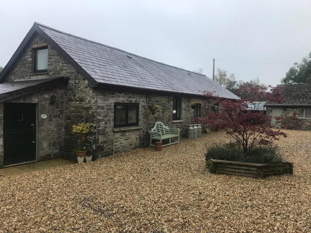 a stone house with a gravel yard in front of it at Cosy Cottages in Llandeilo