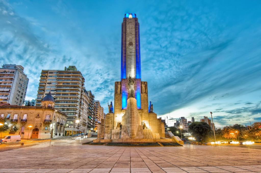 a tall tower in a city at night at Luminosos y modernos departamentos en Rosario in Rosario