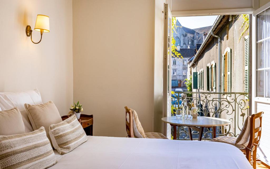 Schlafzimmer mit einem Bett und einem Tisch auf dem Balkon in der Unterkunft Logis Relais de la Source in Saint-Seine-lʼAbbaye