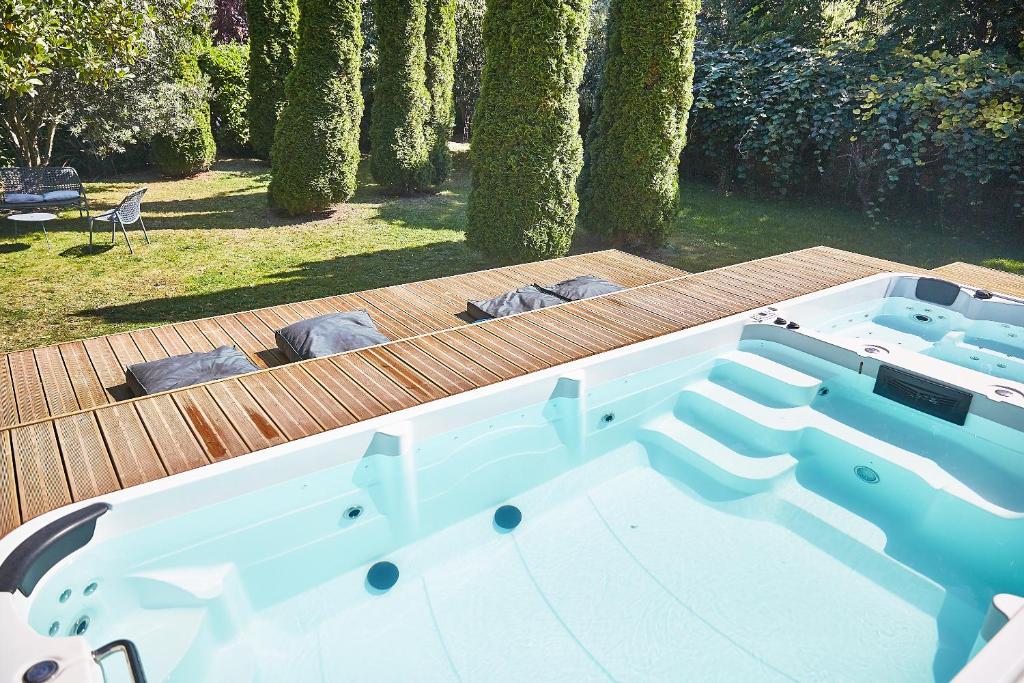 a large bath tub sitting on a wooden deck at Demeure de Manneville - SPA - 1Km des plages de Cabourg in Dives-sur-Mer