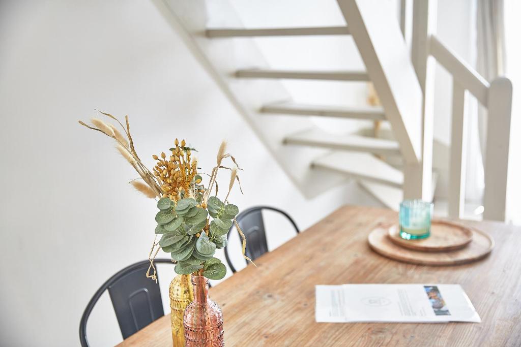 a wooden table with a vase with a plant on it at Demeure de Manneville - SPA - 1Km des plages de Cabourg in Dives-sur-Mer