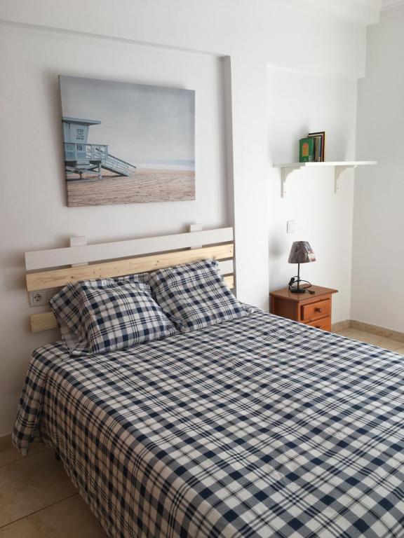 a bedroom with a bed with a checkered blanket at Berlin Lovely in Gran Tarajal